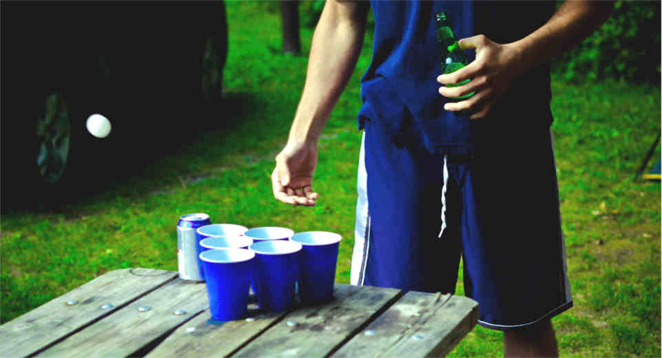 Party Trinkspiel Beer Pong, bei dem man mit einem Tischtennisball in Becher treffen muss