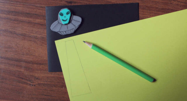 "Crafting a UFO card: Drawing a light beam on yellow clay pape."