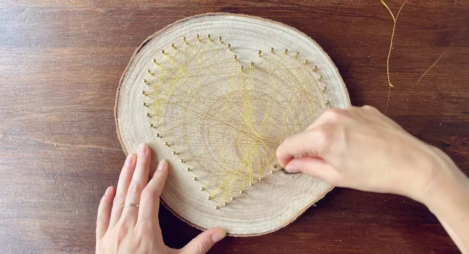 "To make the DIY string art heart, wrap thread crisscross around the nails"