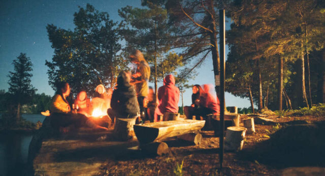 "A bonfire at an fall party creates a cozy atmosphere."